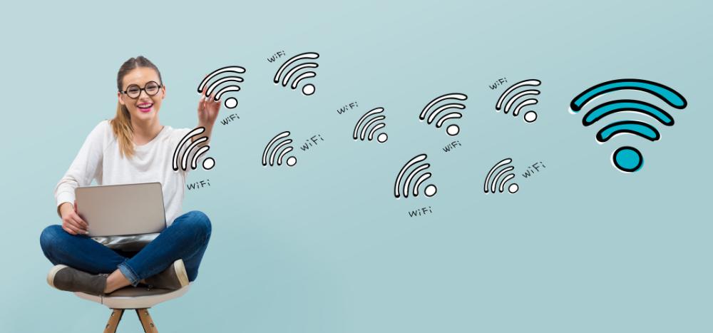 Business WiFi upgrade: A smiling woman sitting cross-legged on a chair with a laptop, surrounded by illustrated WiFi symbols that lead to a large blue WiFi icon on a light teal background.