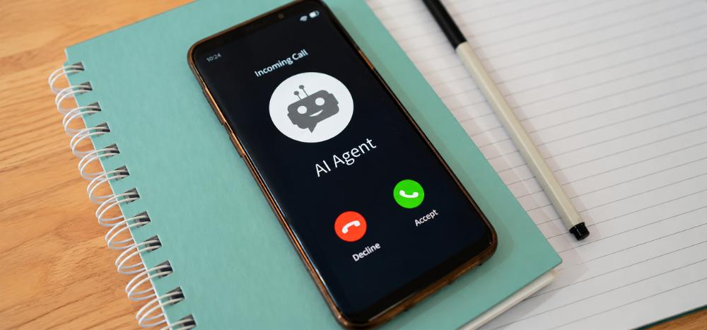 How AI is changing business phone systems header A smartphone on a notebook displaying an incoming call screen from an "AI Agent", with decline and accept buttons.