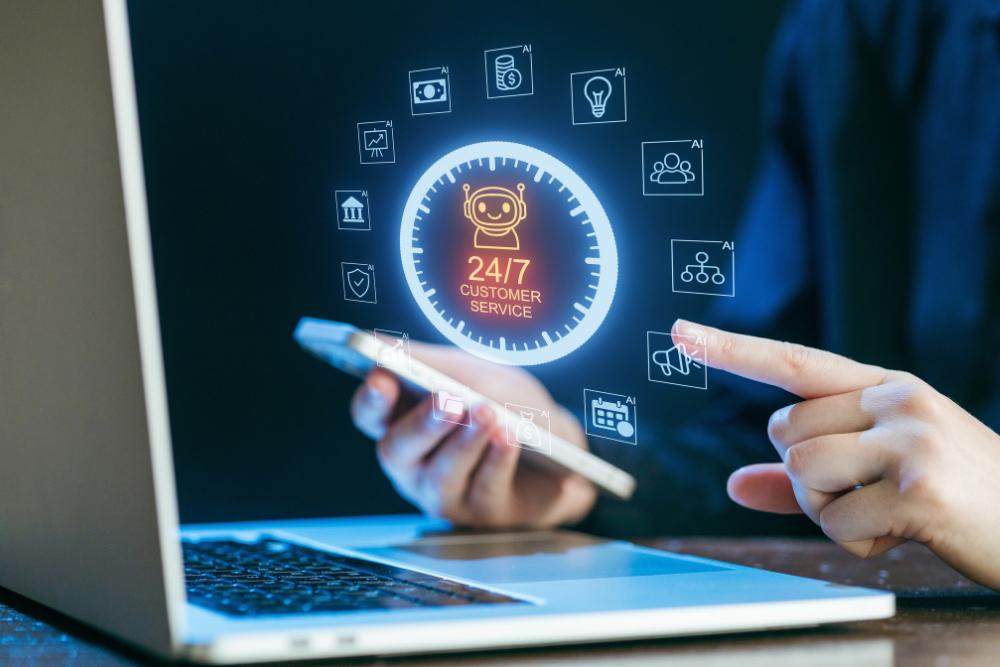 Practical AI tools for small business communication Close-up of hands using a laptop and phone, with digital icons representing AI-powered customer service surrounding a "24/7 Customer Service" graphic.